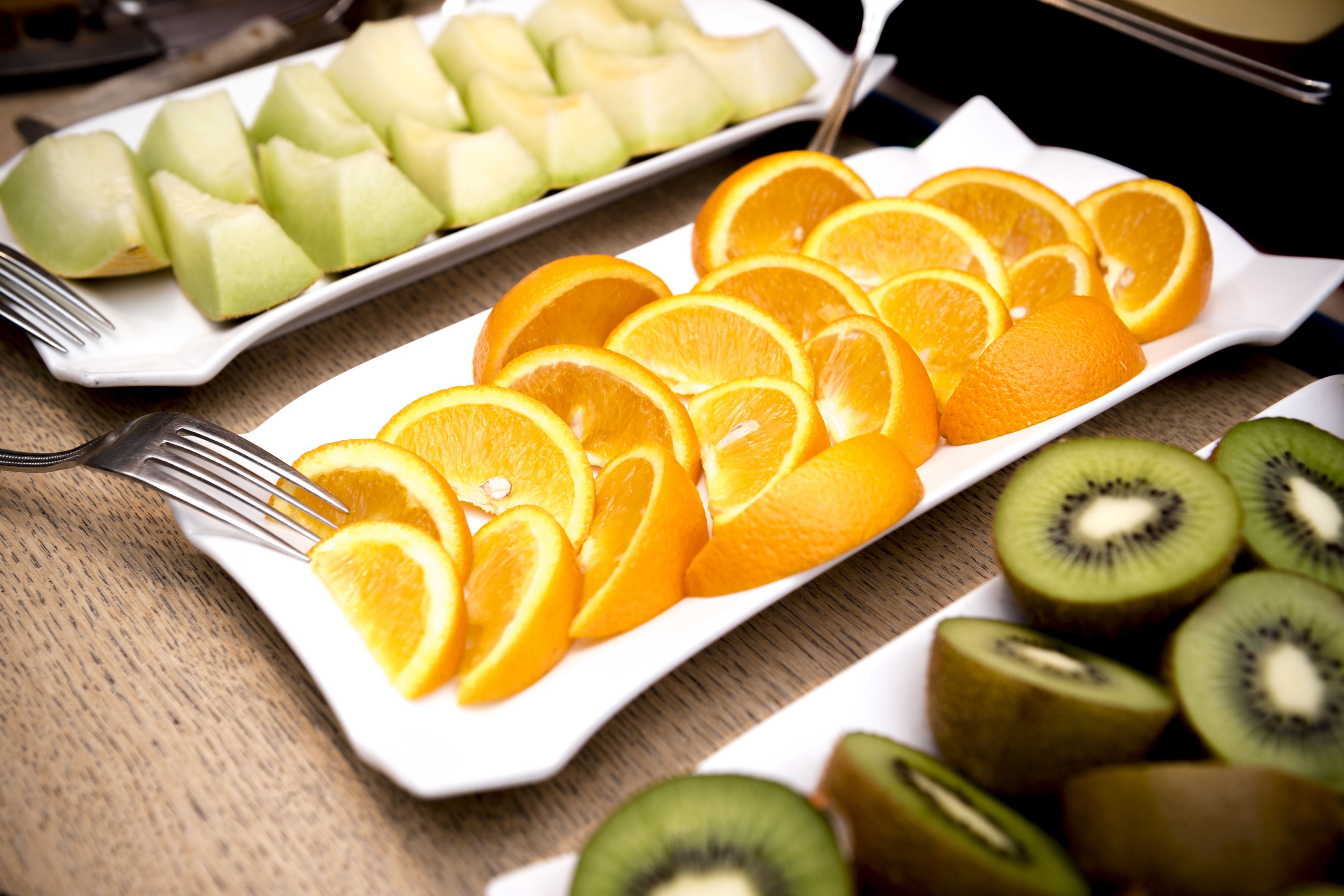 Plato rectangular blanco con rodajas de naranja y kiwi sobre una mesa de madera.