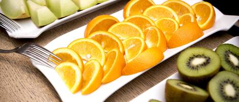 Plato rectangular blanco con rodajas de naranja y kiwi sobre una mesa de madera.