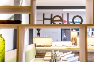 Un interior moderno con un letrero que dice 'Hello', estantes de madera y una zona de estar con mesas y sillas.
