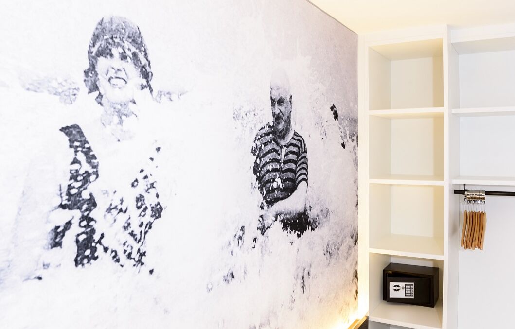 Una habitación con un cuadro abstracto grande en la pared, un estante blanco con una caja fuerte negra y una barra para cortina con cortina blanca.