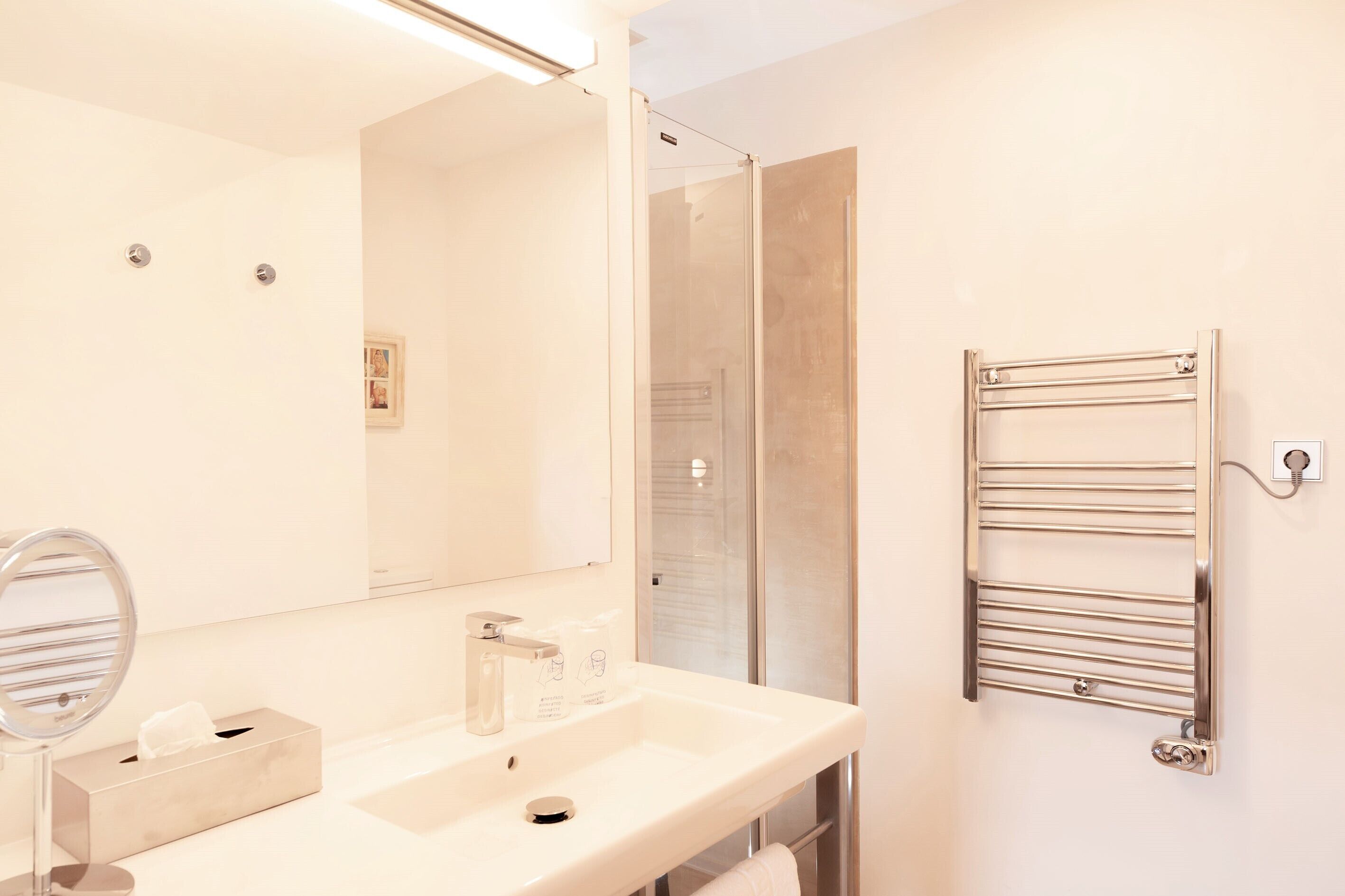 A modern bathroom with a large mirror, a sink, and a towel rack.