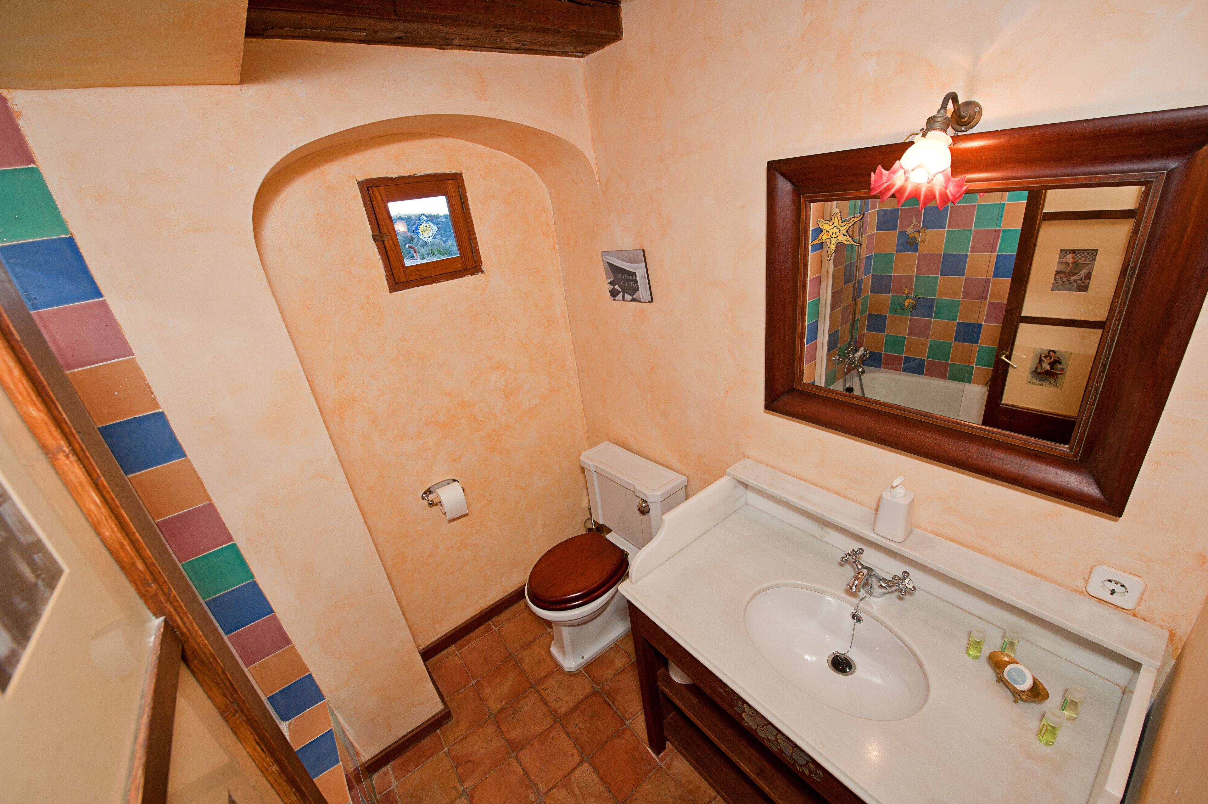 A bathroom with a toilet, sink, and mirror.
