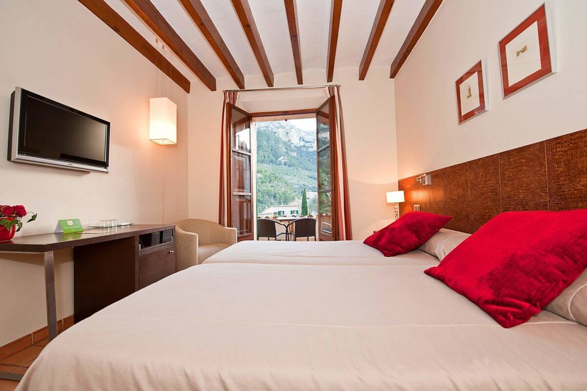 Une chambre d’hôtel avec un lit, un bureau, une télévision et une vue sur la montagne.