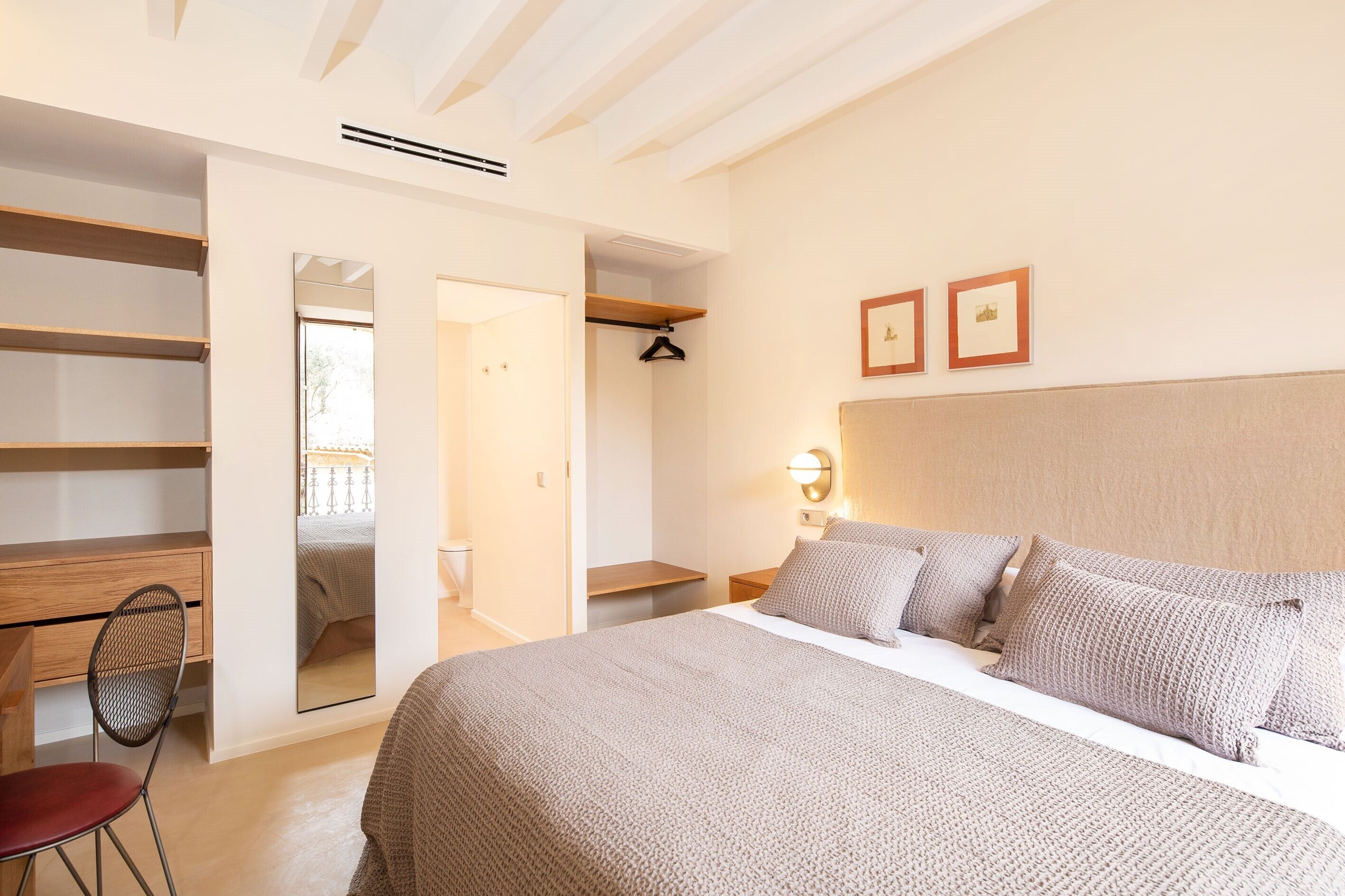 Un dormitorio con una cama grande, un escritorio, una silla y un vestidor.