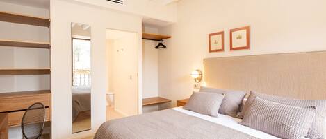 Un dormitorio con una cama grande, un escritorio, una silla y un vestidor.