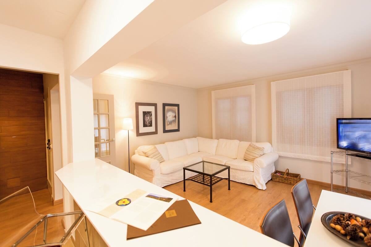 Un salon moderne avec un canapé blanc, une table basse en verre et un téléviseur à écran plat.