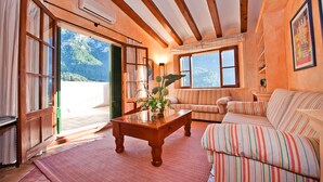 Un salon chaleureux avec une table basse en bois, un canapé à rayures et de grandes fenêtres donnant sur une vue imprenable sur les montagnes.