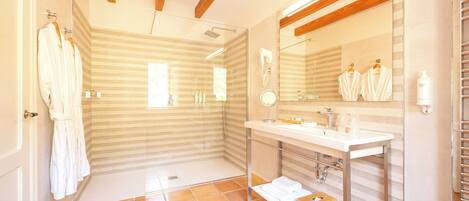 A modern bathroom with a glass shower, a large mirror, and a vanity with a sink and towel rack.