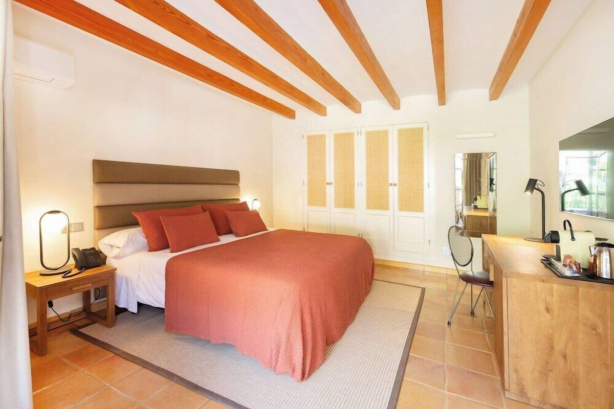 Une chambre à coucher comprenant un lit, une table de chevet, une lampe et un bureau avec une chaise.