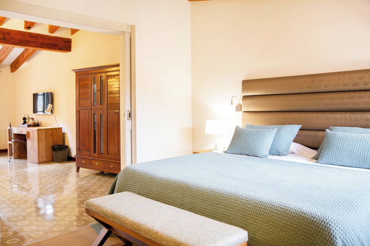 Une chambre à coucher avec un grand lit, une armoire en bois, un bureau et une chaise.