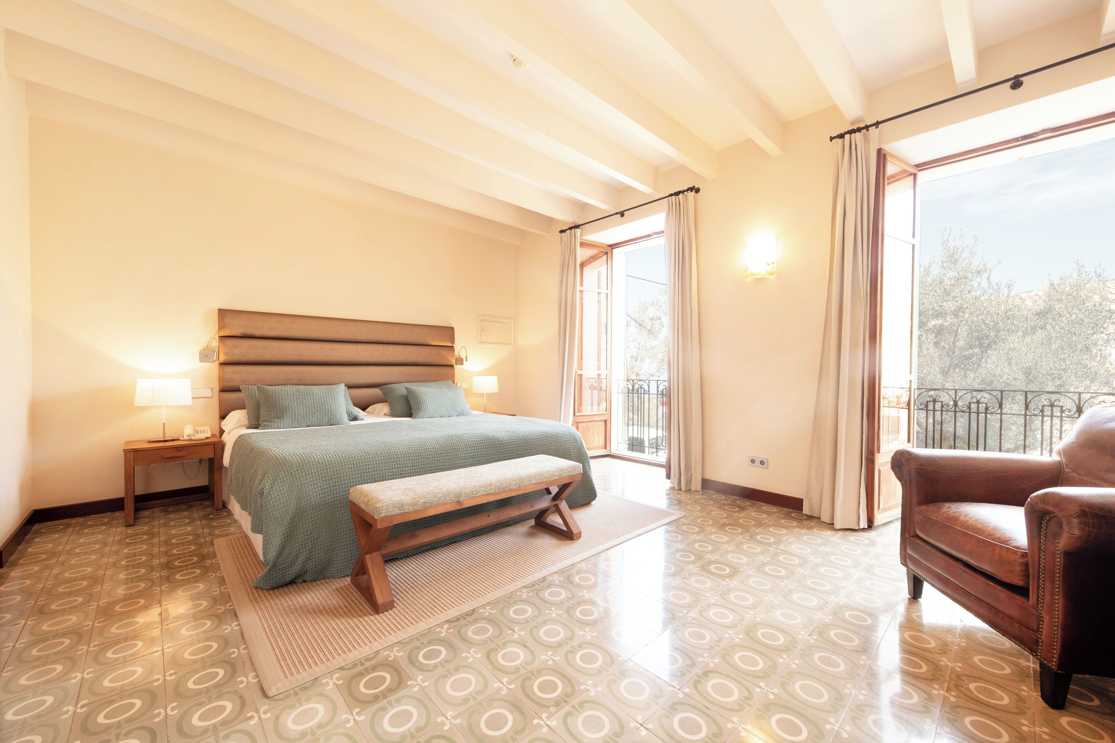 Una camera da letto con un letto, una panca, un comodino e una sedia.