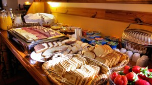 A buffet with various food items including bread, fruits, and beverages. - Hotel Rural Quinta da Geia (Oliveira do Hospital)