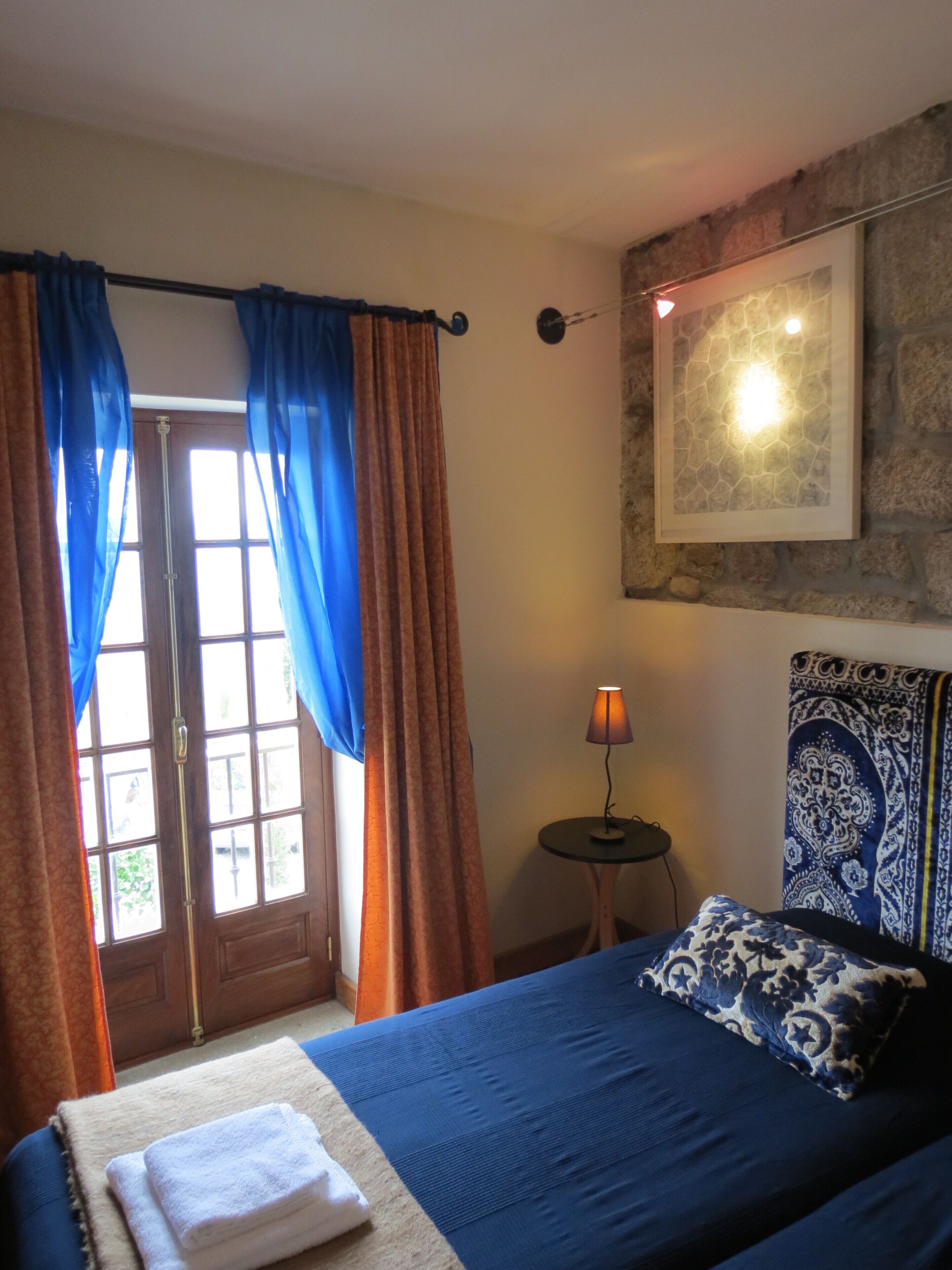 A bedroom with a bed, a nightstand, a lamp, and a window with curtains.