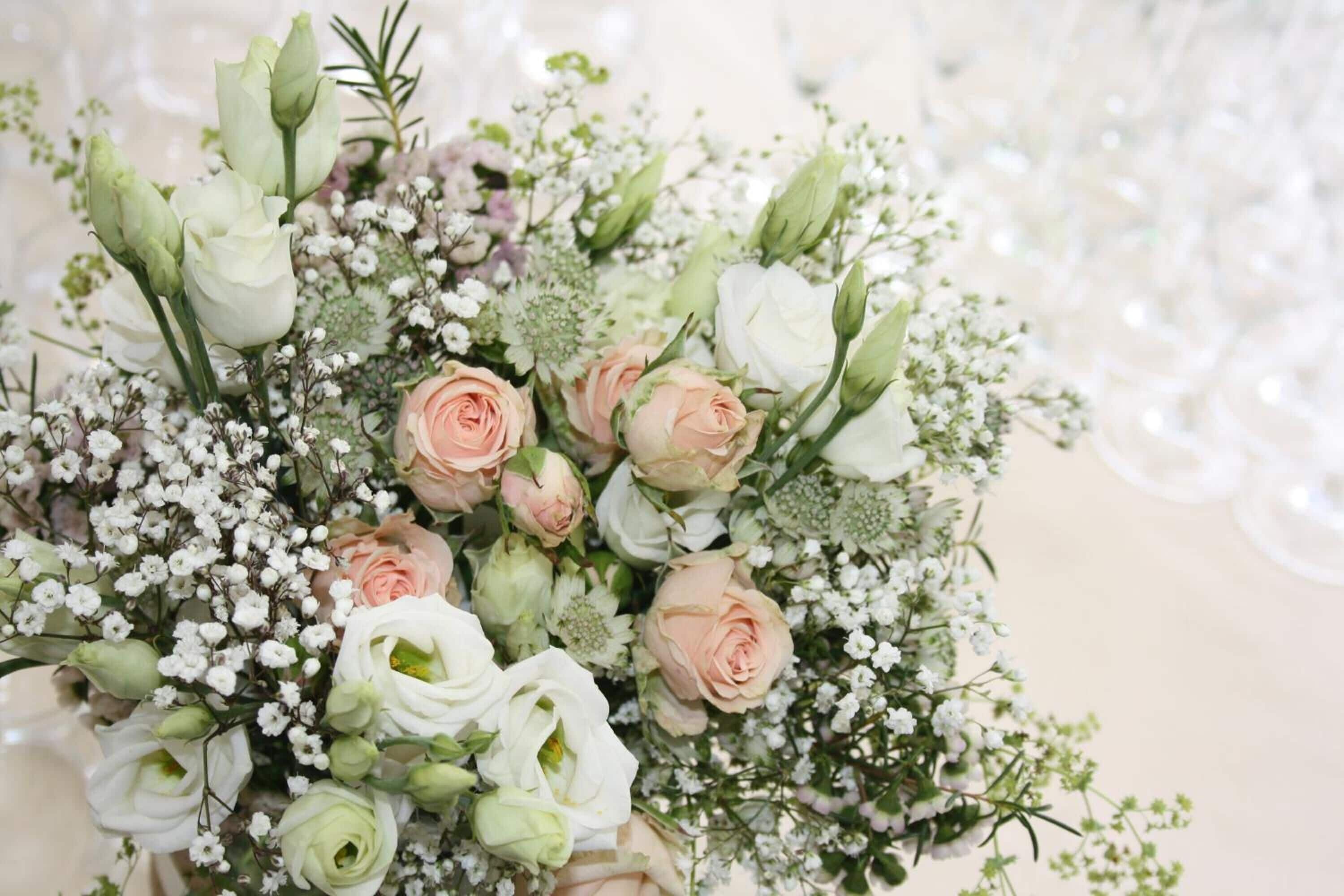 Un bouquet di rose bianche e pesca, con piccoli fiori bianchi e del verde.