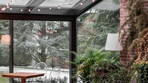 Une pièce moderne avec un plafond en verre, une table en bois et une plante en pot.
