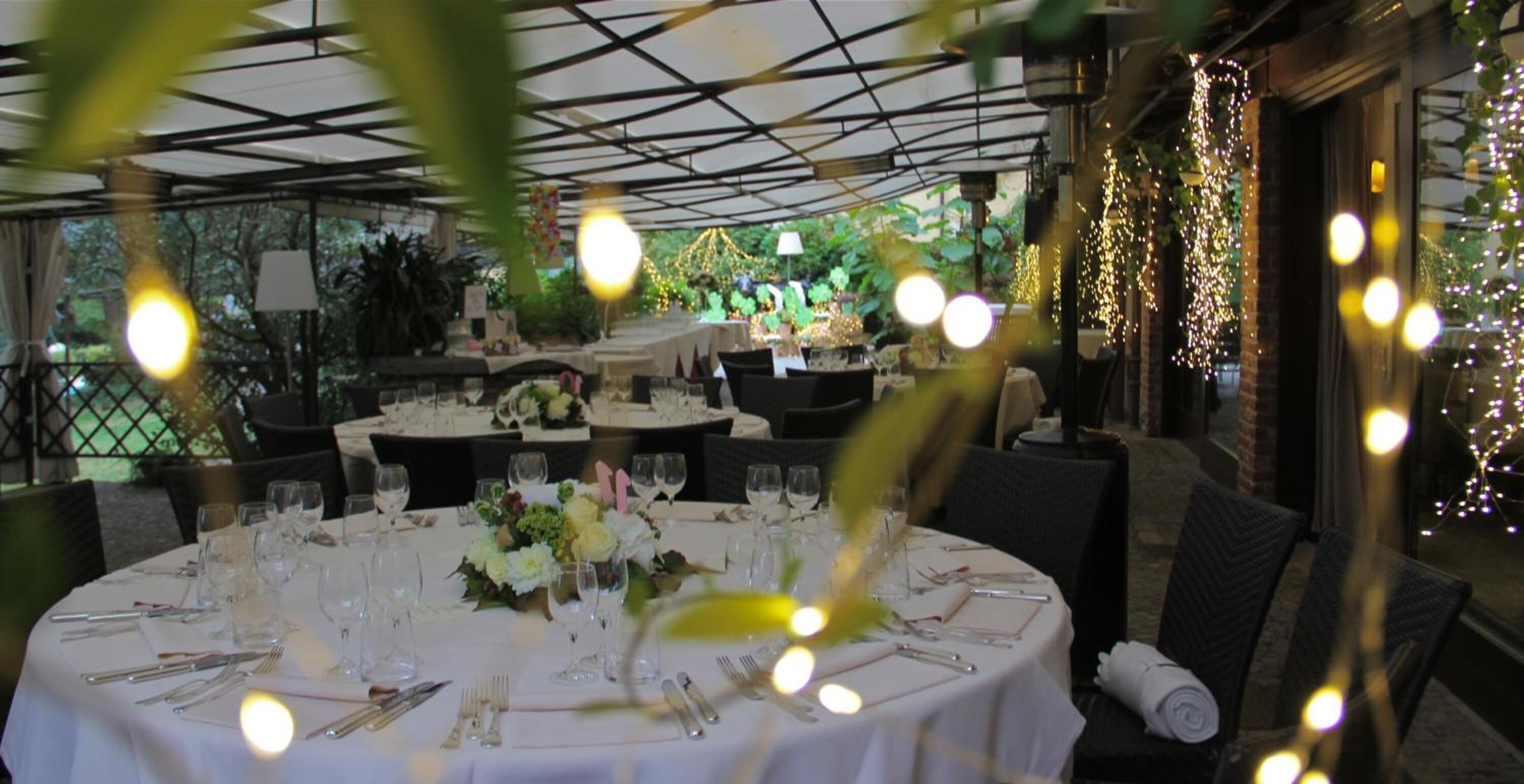 A restaurant with round tables set for dining, featuring white tablecloths and floral centerpieces.