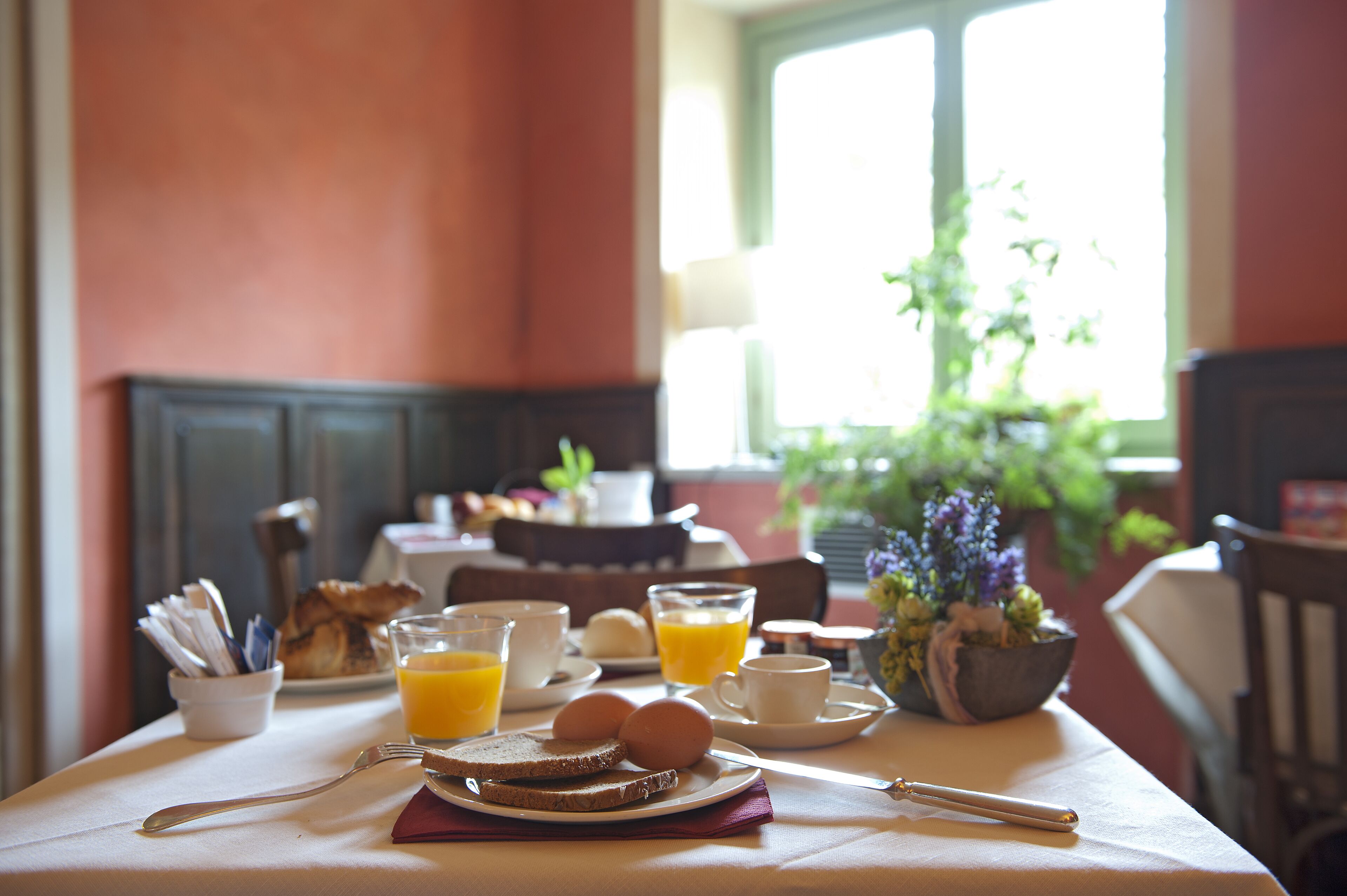 Taula de l'esmorzar amb torrades, ous, suc d'aranja i una tassa de cafè.