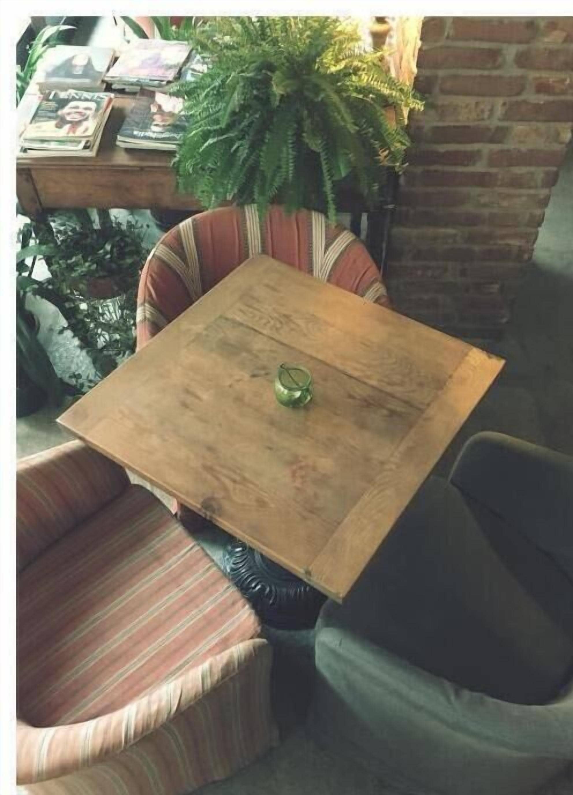 Une table en bois surmontée d’un récipient en verre, entourée de chaises rembourrées à rayures.