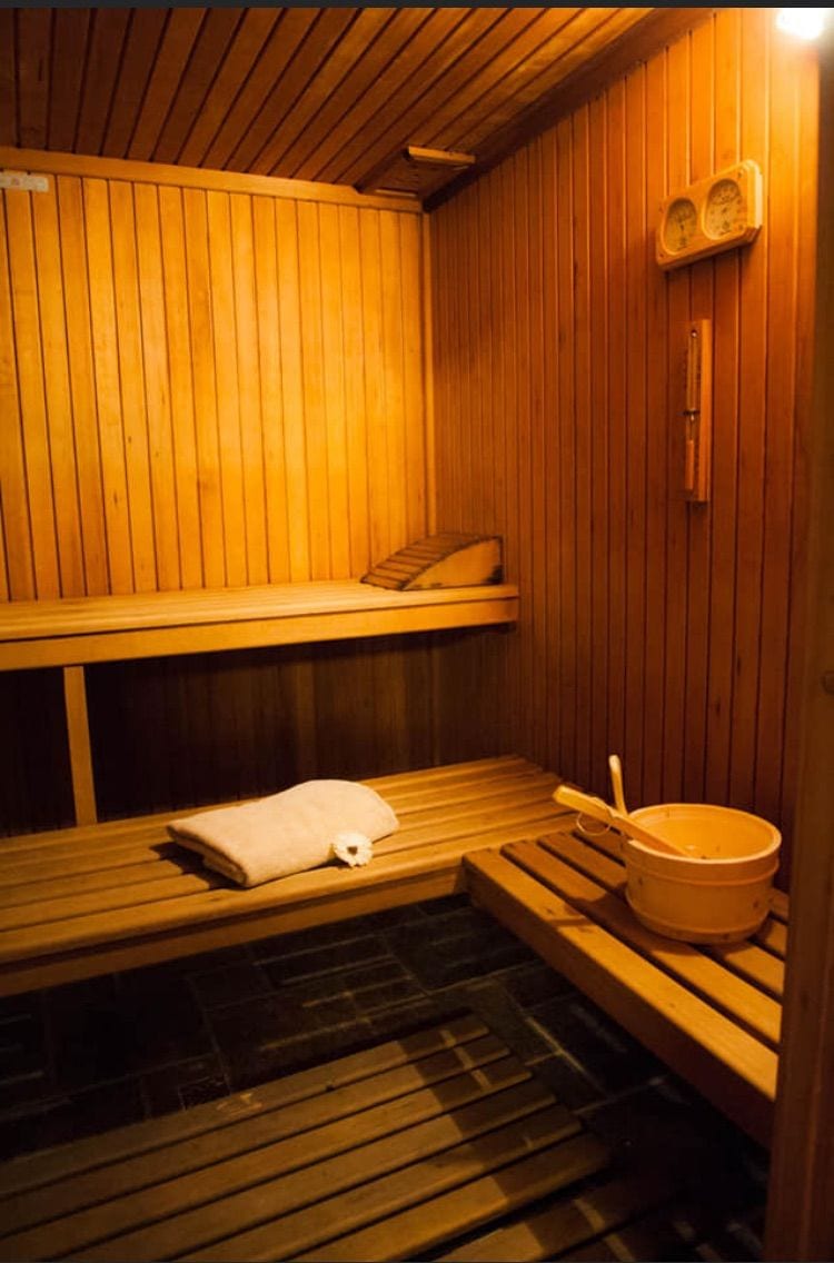 En træsauna med bænke, en bænk med et håndklæde og en spand.
