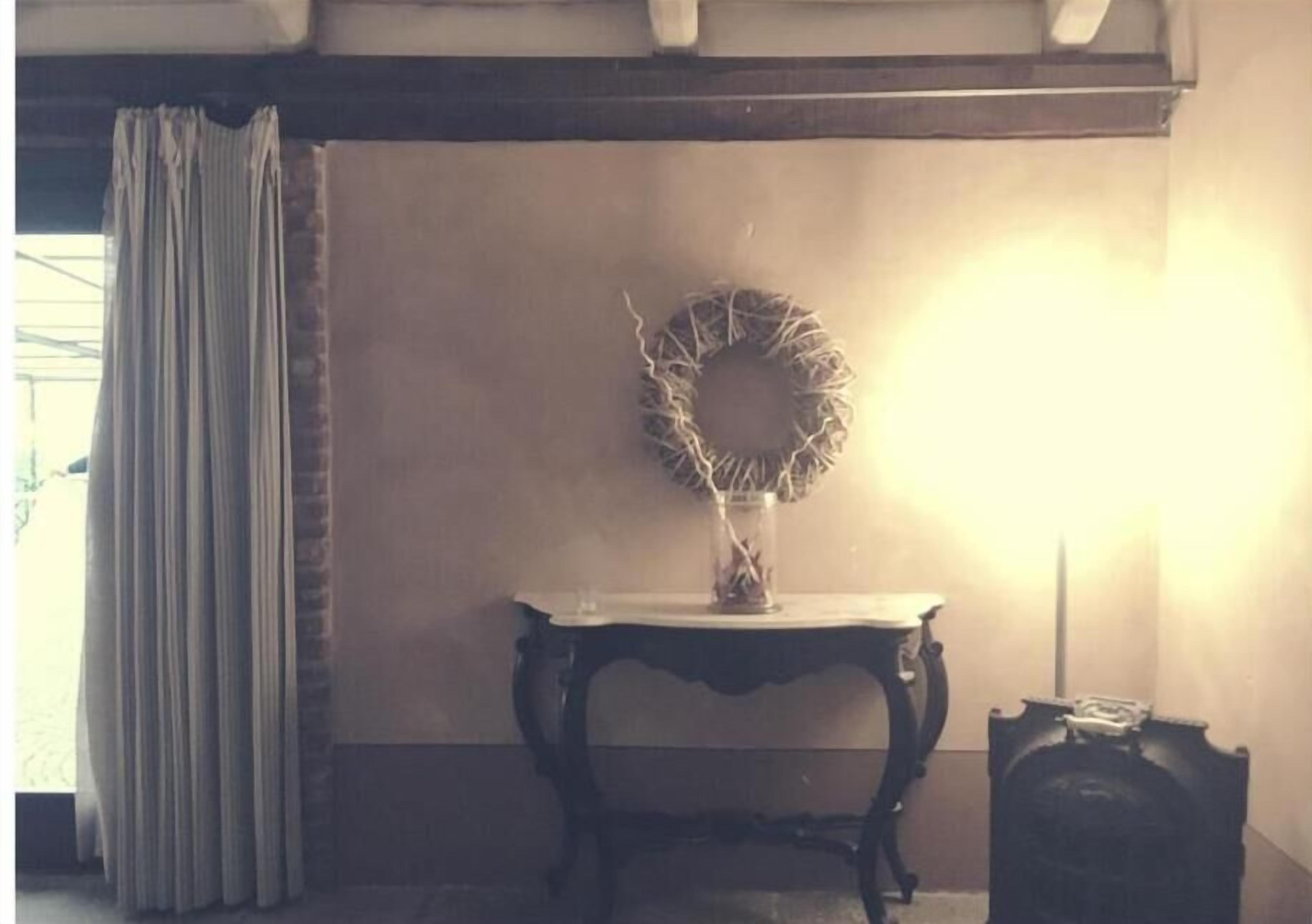 Una stanza con un tavolo in legno scuro, una ghirlanda appesa al muro e una lampada.