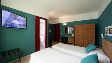 Camera d'albergo con due letti, televisione, bagno e una porta rossa.