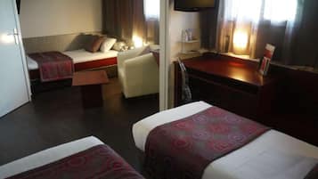 Habitación de hotel con dos camas, un escritorio, una silla, un televisor y una ventana con cortinas.