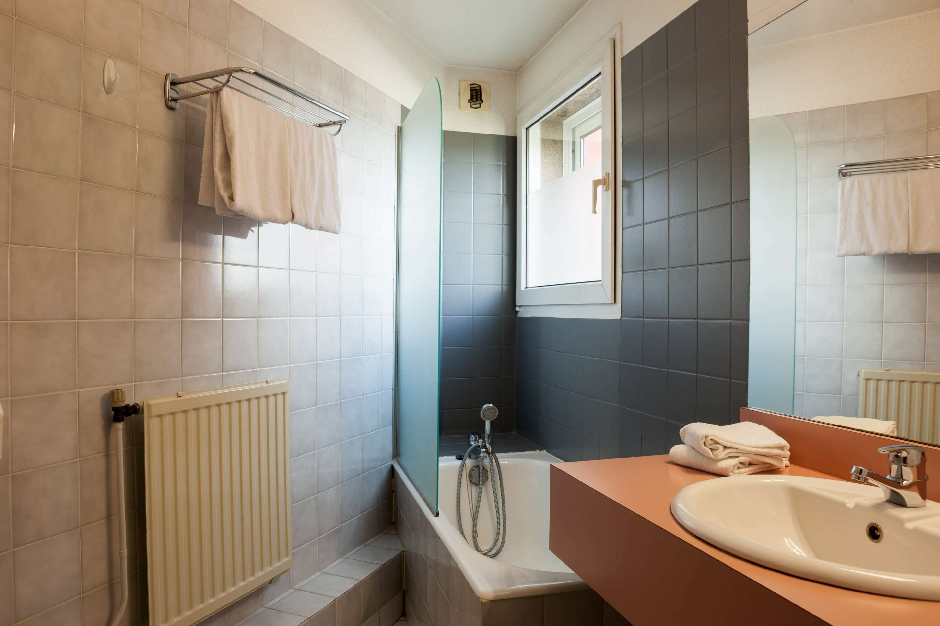 Une salle de bain avec une baignoire, une douche, un lavabo et un miroir.