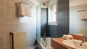 Une salle de bain avec une baignoire, une douche, un lavabo et un miroir.