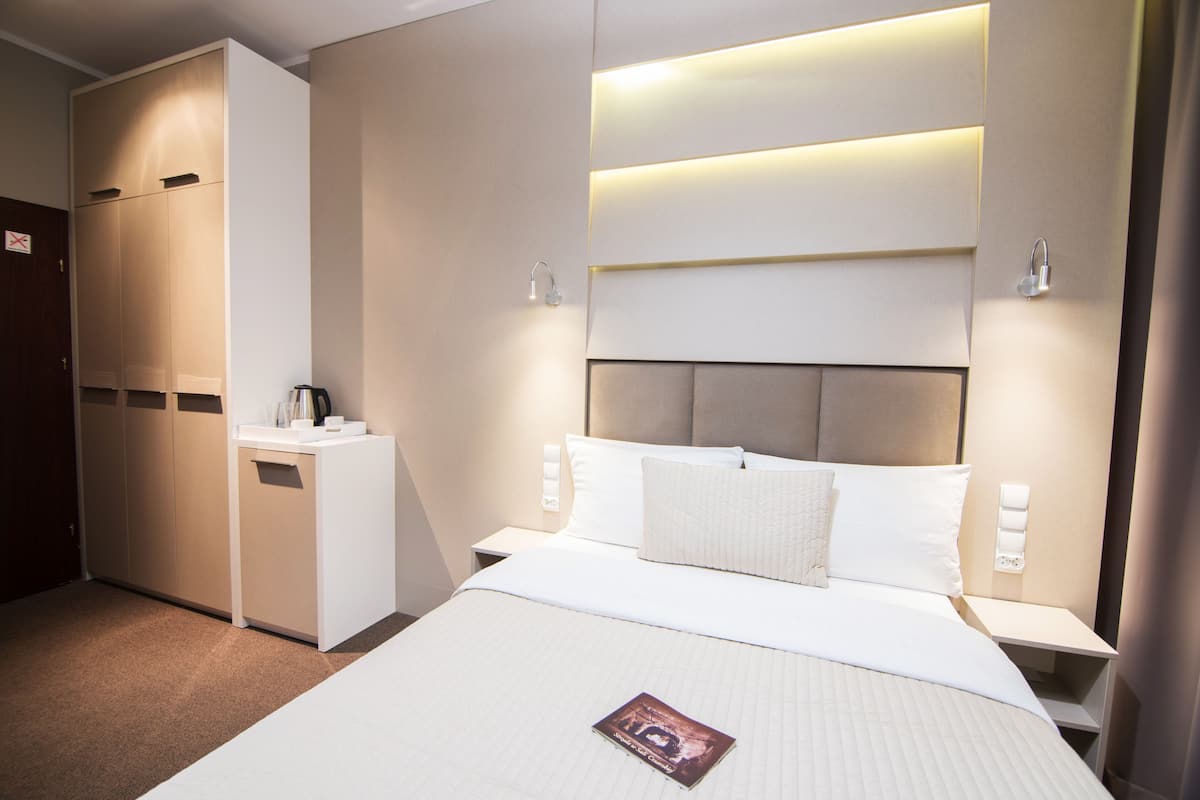 A hotel room with a bed, bedside tables, a desk, and a wardrobe.