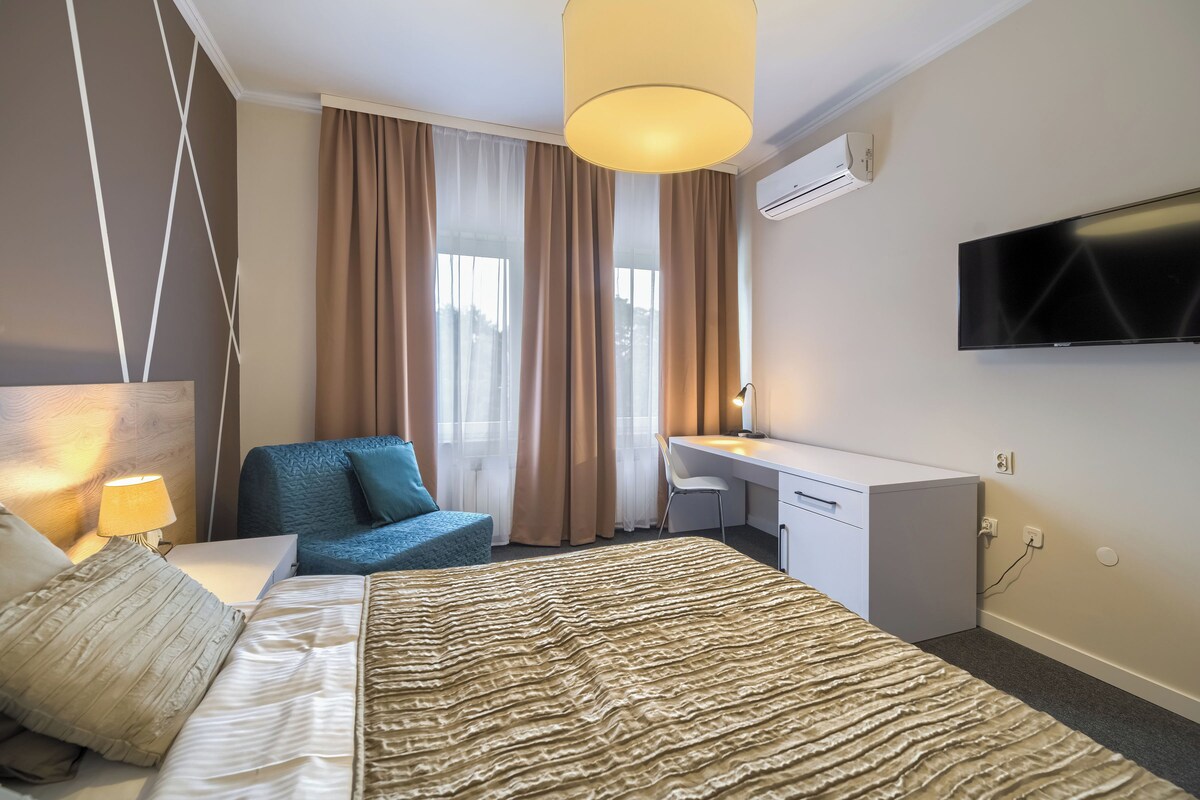 Habitación de hotel con cama, escritorio, silla, televisión y aire acondicionado.