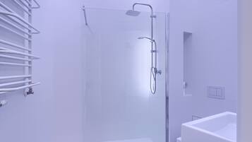 Un baño moderno con cabina de ducha de vidrio, un lavabo blanco y un perchero para toallas.