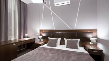 Una habitación de hotel moderna con una cama grande, mesitas de noche, un escritorio y una ventana con cortinas.