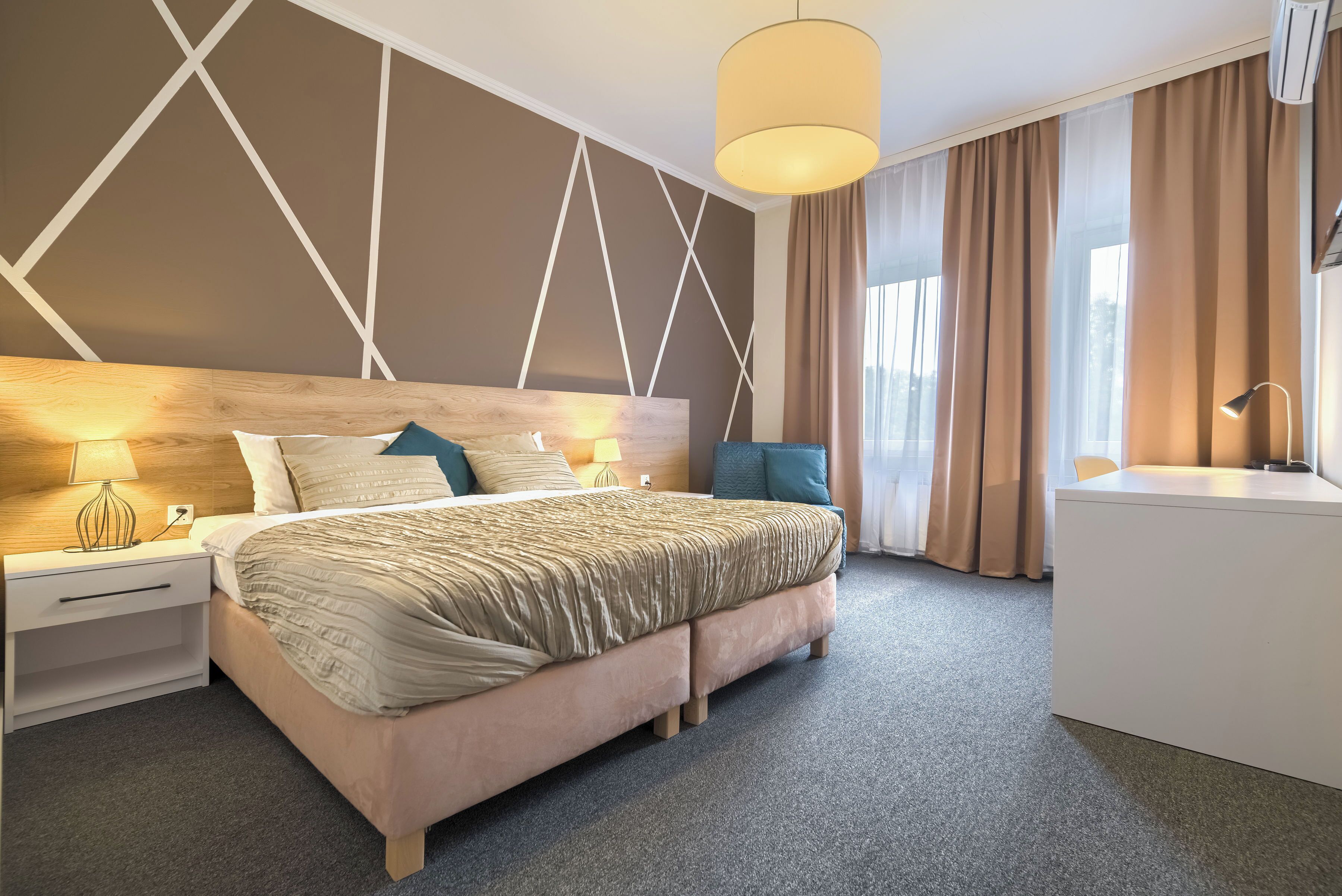 Una habitación de hotel moderna con una cama grande, mesitas de noche, un escritorio y vistas al exterior.