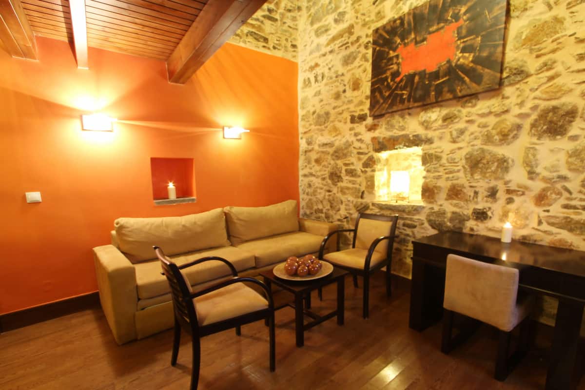 A cozy living area with a stone wall, a wooden ceiling, and a beige sofa.