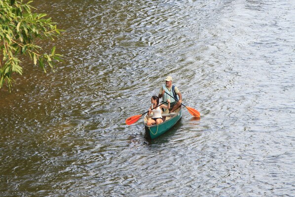 Una embarcación estrecha con dos personas remando en un río.