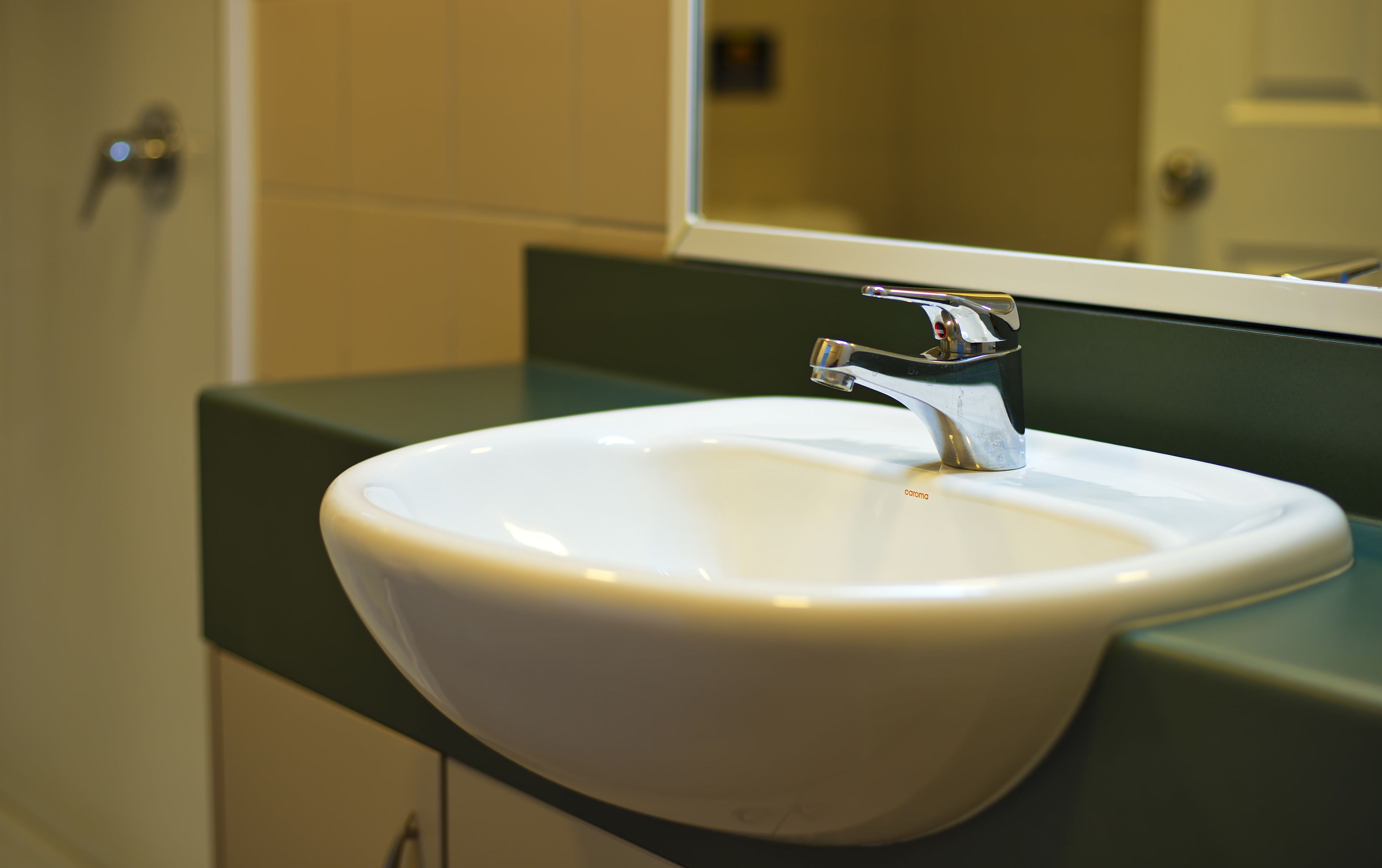 A white sink with a chrome faucet in a bathroom with green countertops.