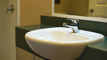 A white sink with a chrome faucet in a bathroom with green countertops.