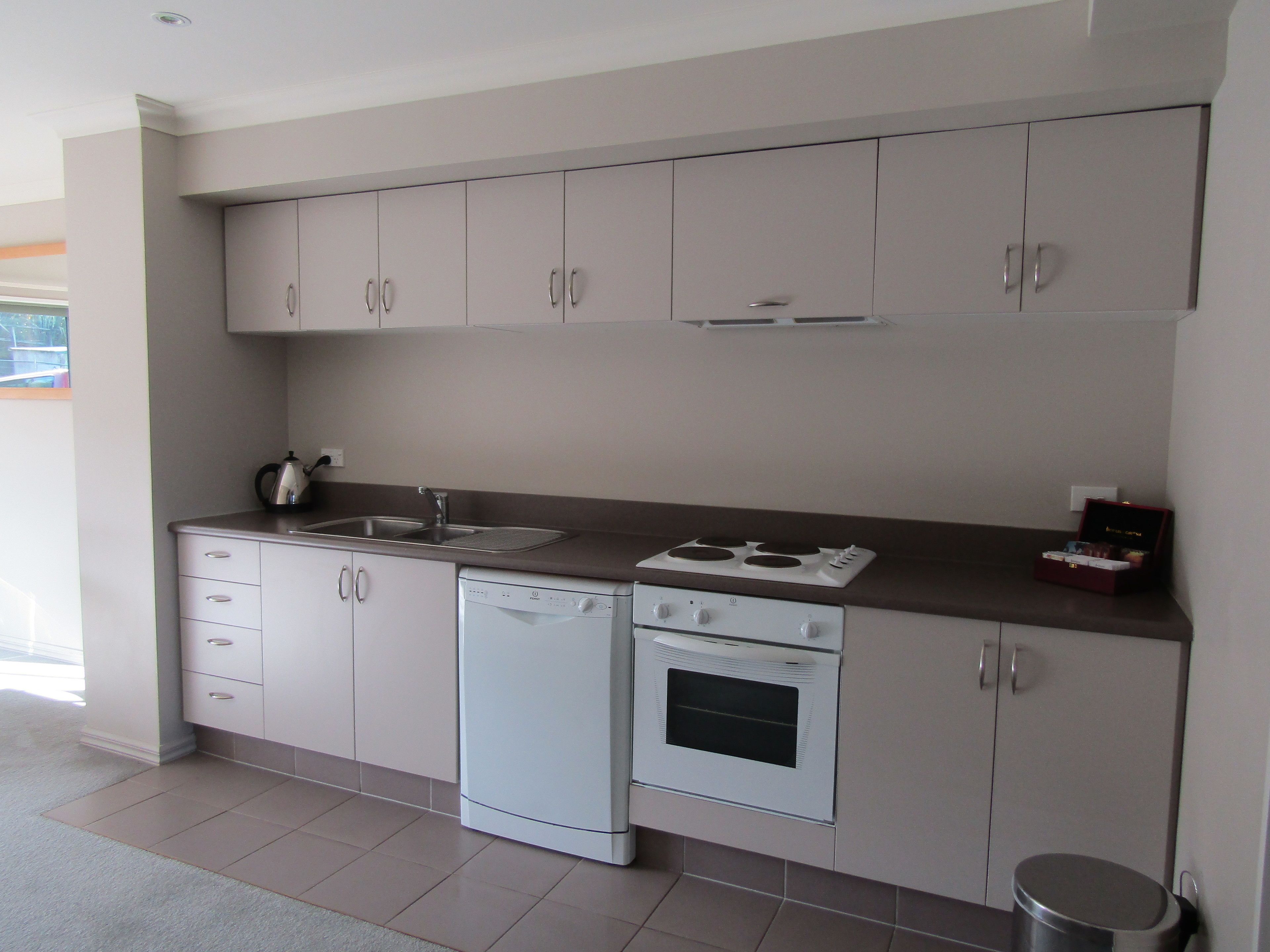 Una cocina moderna con armarios blancos, lavavajillas, horno y placa de cocina.