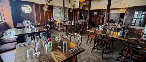 Un restaurant avec des tables et des chaises en bois, et des têtes de cerfs ornées de bois sur les murs.