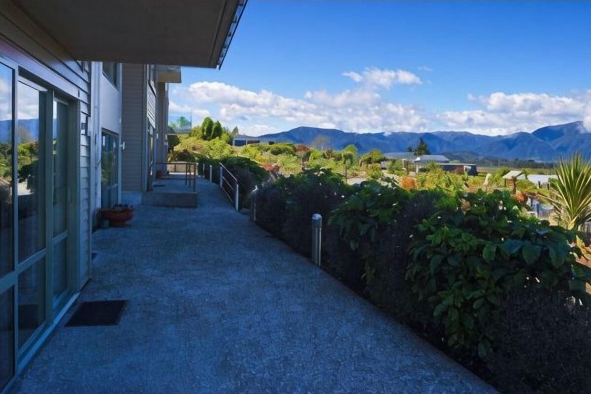 A building with a covered walkway, glass doors, and a view of mountains.