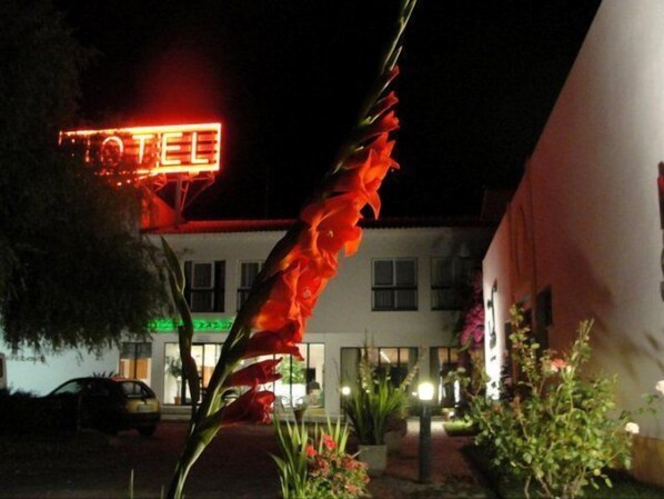Ein Hotel mit leuchtendem Neonlicht, einem davor parkenden Auto und einem gut beleuchteten Eingang.