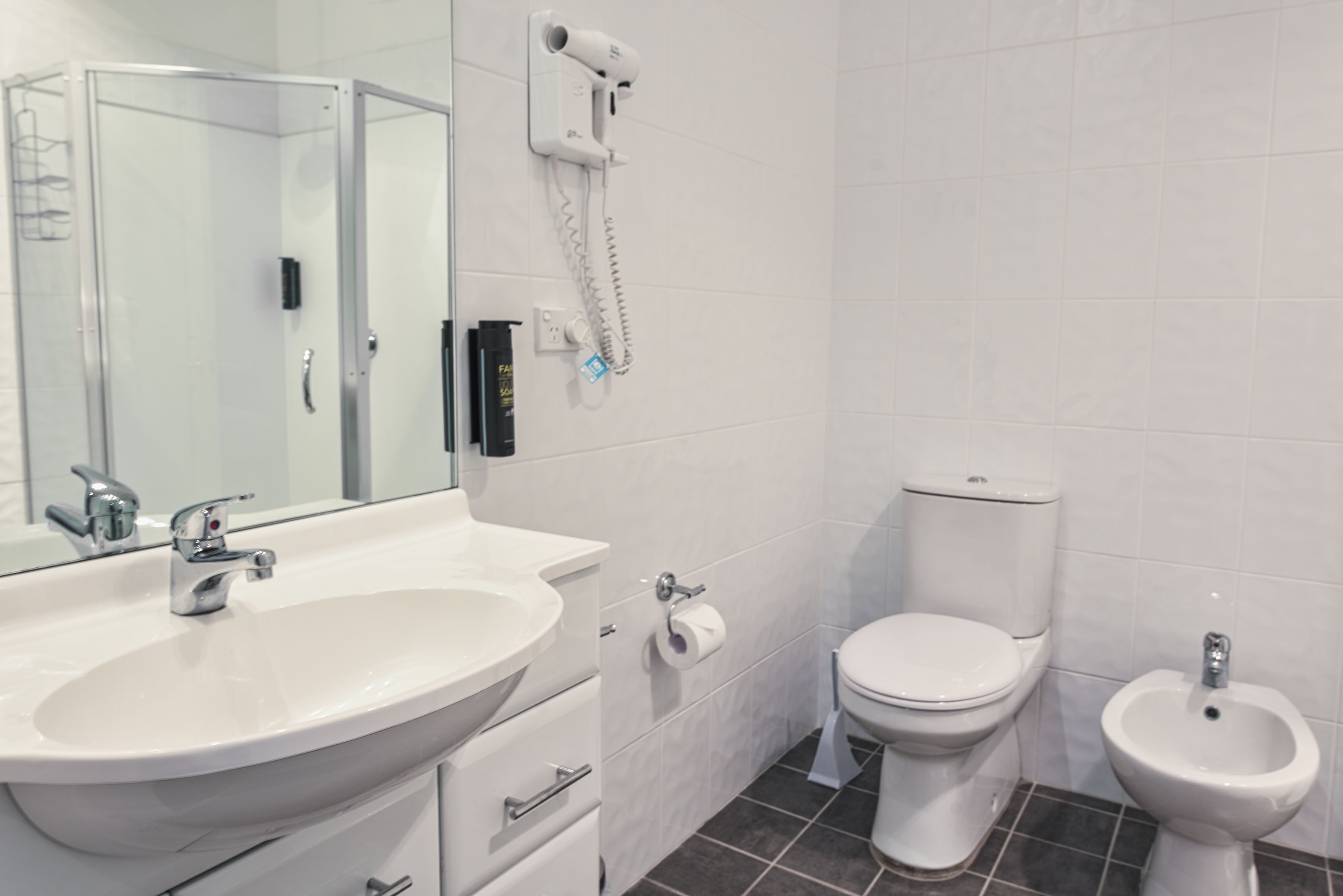 Ein modernes Badezimmer mit einem weißen Waschbecken, einer Toilette und einem Bidet.