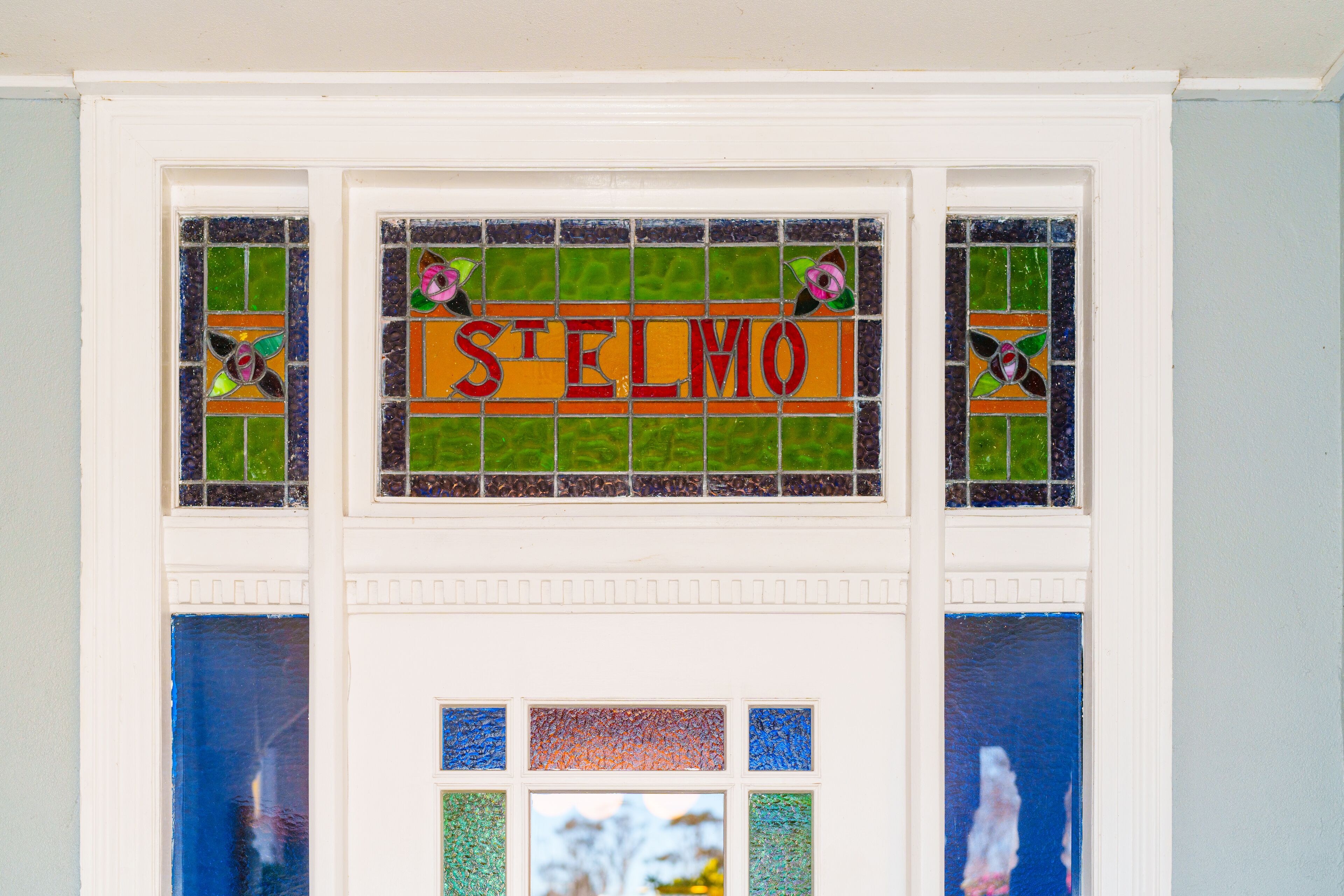 A stained glass window with the word "STELMO" and decorative elements.