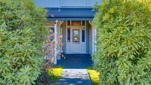 A building with a covered porch and a door with a sign. - Blue Mountains Heritage Motel (Katoomba)