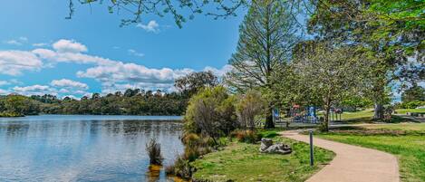 A park with a lake, a playground, and a walking path.