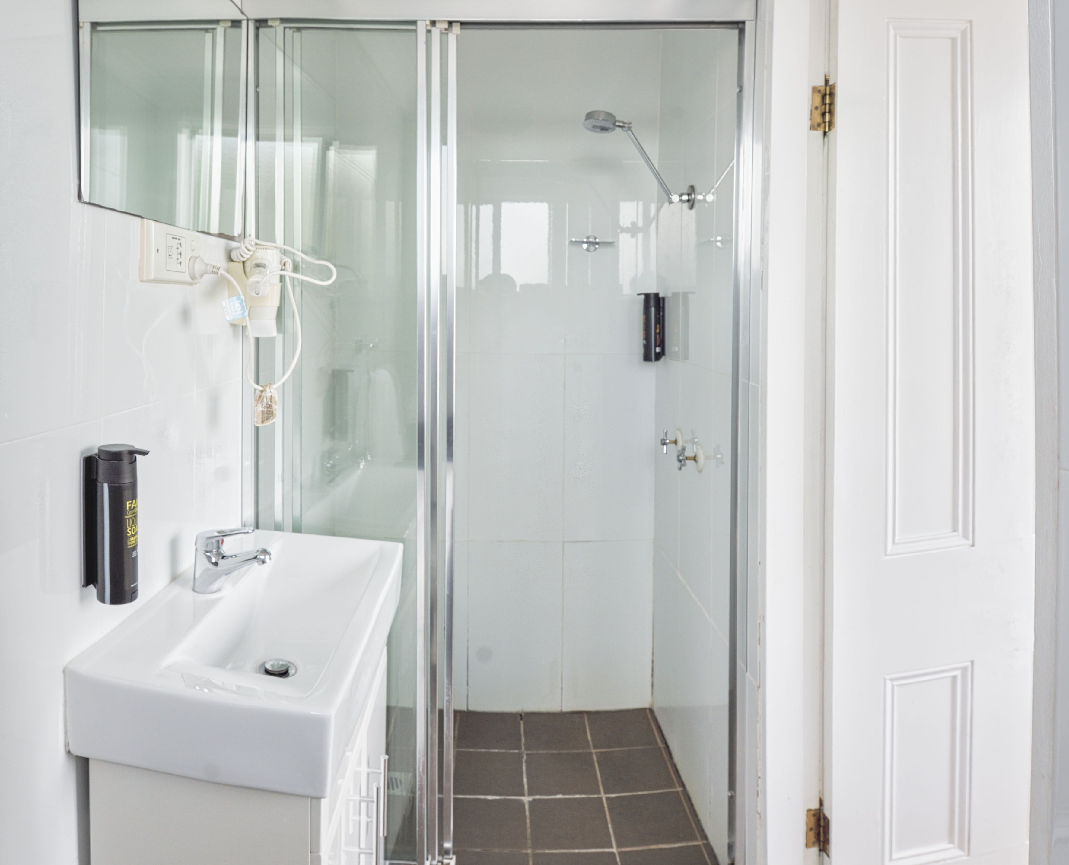 Un baño moderno con cabina de ducha de vidrio, un lavabo blanco y un espejo.