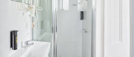 Un baño moderno con cabina de ducha de vidrio, un lavabo blanco y un espejo.