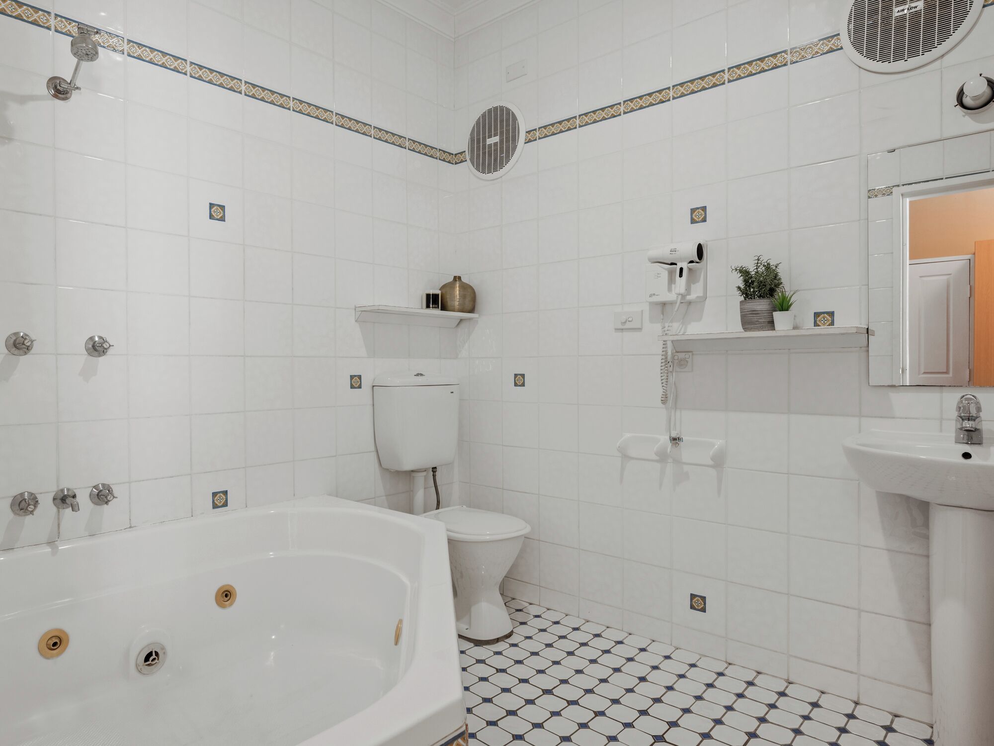 A bathroom with a bathtub, toilet, sink, and a shower with a handheld dryer.