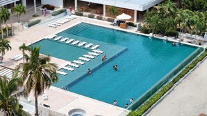 A large rectangular pool with multiple lanes, surrounded by lounge chairs and palm trees. - Hotel Tamacá Beach Resort (Santa Marta)
