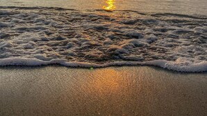 A beach with waves and a sunset in the background. - Hotel Tamacá Beach Resort (Santa Marta)